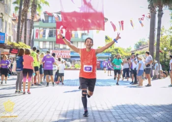 Türk bayrakları altında neşeyle koşan bir maraton koşucusu.