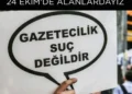 Gazetecilik suç değildir" yazılı bir döviz tutan el.