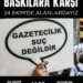 Gazetecilik suç değildir" yazılı bir döviz tutan el.