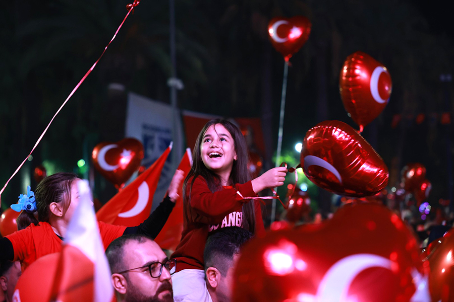 Türk bayraklı balonlarla kutlama yapan neşeli kız çocuğu.