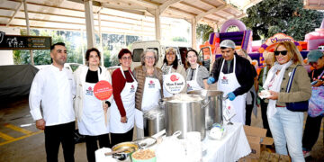 Slow Food Bodrum etkinliğinde yemek dağıtan gülümseyen grup.