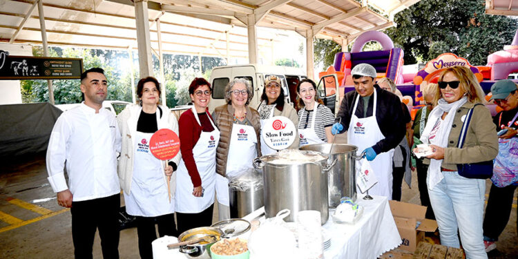 Slow Food Bodrum etkinliğinde yemek dağıtan gülümseyen grup.