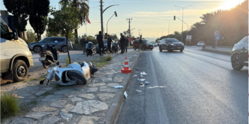 Yol kenarında kaza yapmış, yan yatmış beyaz bir motosiklet.