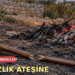 Yerde kırılmış bir baston ve arkada yanan temizlik ateşi.