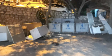 Sokak kenarında çöp konteynerleri ve atılmış eski mobilyalar.