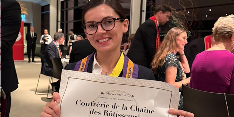 Chaîne des Rôtisseurs sertifikasını tutan gülümseyen kadın sommelier.