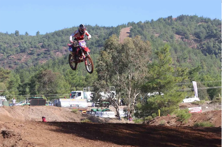 Havada zıplayan kırmızı motokros motosikleti ve sürücüsü.