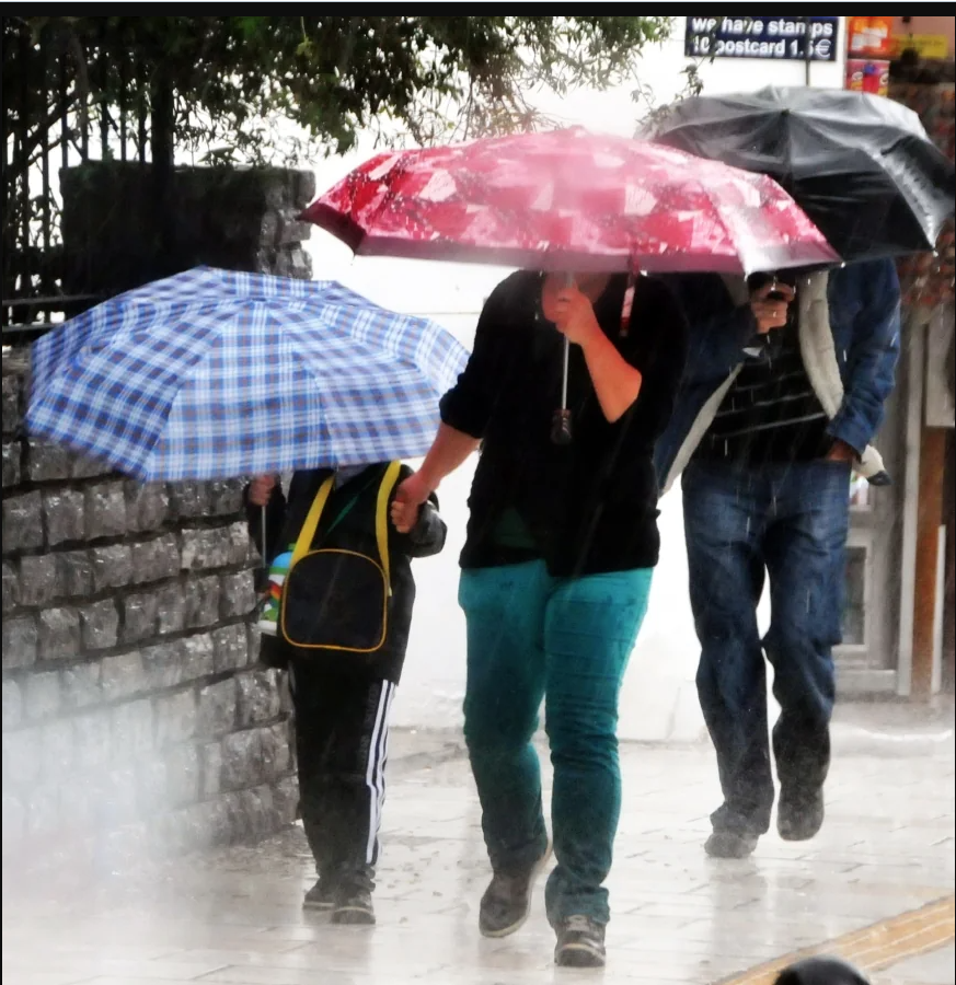 Yağmurda şemsiyeleriyle yürüyen insanlar.