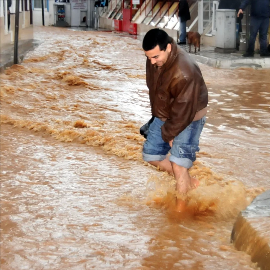 Sel sularının ortasında çıplak ayakla yürüyen adam.