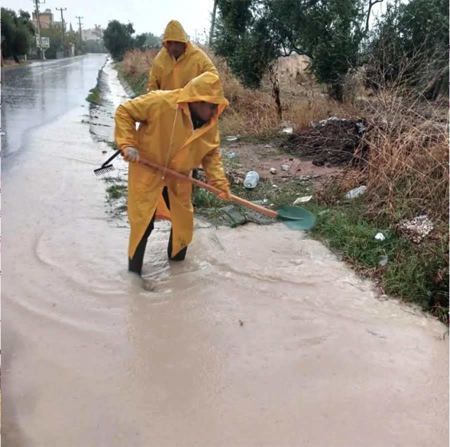 Sarı yağmurluklu işçiler su baskınında temizlik çalışması yapıyor.