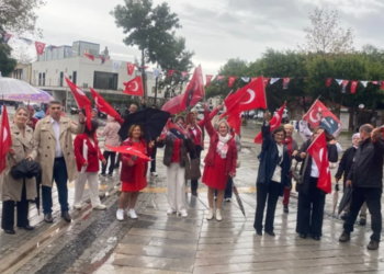 Türk bayrakları sallayan coşkulu bir grup insan.