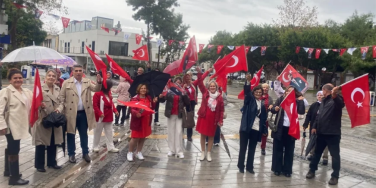 Türk bayrakları sallayan coşkulu bir grup insan.