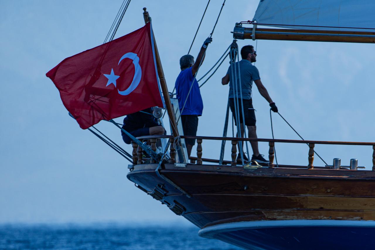 Türk bayraklı yelkenli teknenin güvertesinde çalışan mürettebat.