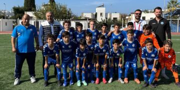 Sahada toplu fotoğraf çektiren mavi formalı çocuk futbol takımı.