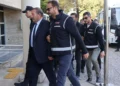 Polislerin eşlik ettiği takım elbiseli bir şüpheli.
