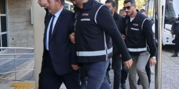 Polislerin eşlik ettiği takım elbiseli bir şüpheli.