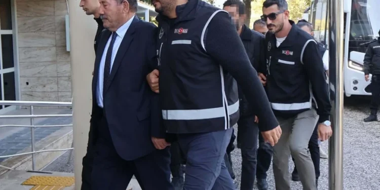 Polislerin eşlik ettiği takım elbiseli bir şüpheli.