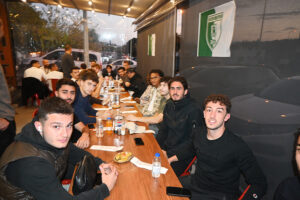 Bir yemek masası etrafında toplanmış genç erkek grubu.