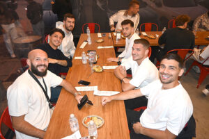 Bir restoranda masanın etrafında gülümseyen bir grup genç adam.
