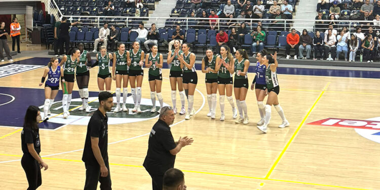 Voleybol sahasında kutlama yapan kadın sporcular ve teknik ekip.