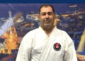 Beyaz karate kıyafeti giymiş orta yaşlı bir adamın portresi.