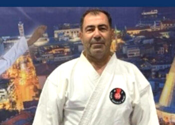 Beyaz karate kıyafeti giymiş orta yaşlı bir adamın portresi.