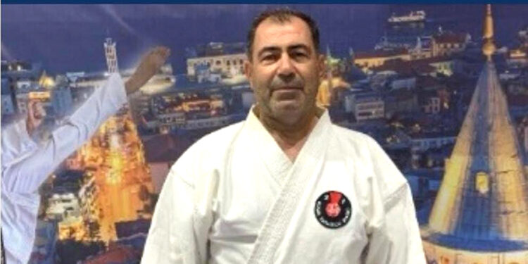 Beyaz karate kıyafeti giymiş orta yaşlı bir adamın portresi.