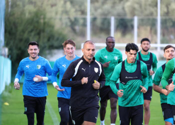 Antrenman sahasında koşan futbolcular ve teknik ekip.