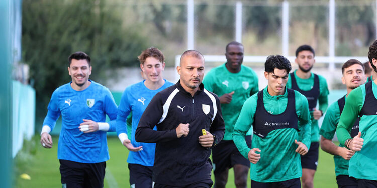 Antrenman sahasında koşan futbolcular ve teknik ekip.