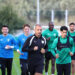 Antrenman sahasında koşan futbolcular ve teknik ekip.