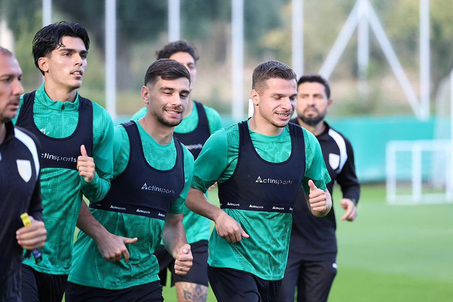 Yeşil formalı futbolcular antrenmanda koşu yaparken.