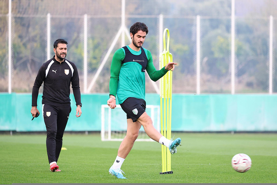 Yeşil sahada şut antrenmanı yapan profesyonel bir futbolcu.