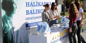 Halikarnas Balıkçısı temalı tanıtım standında broşür dağıtan görevliler ve ziyaretçiler.